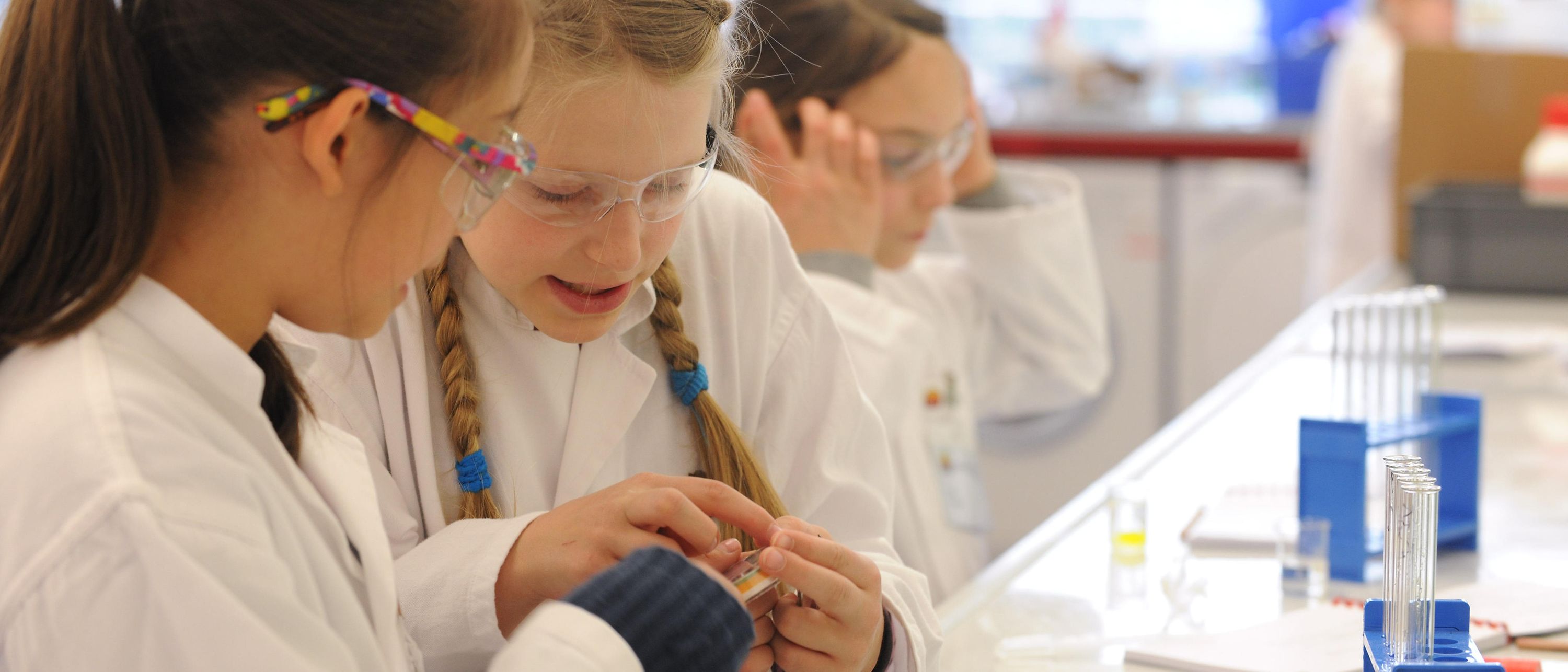 two girls in lab coats at bench