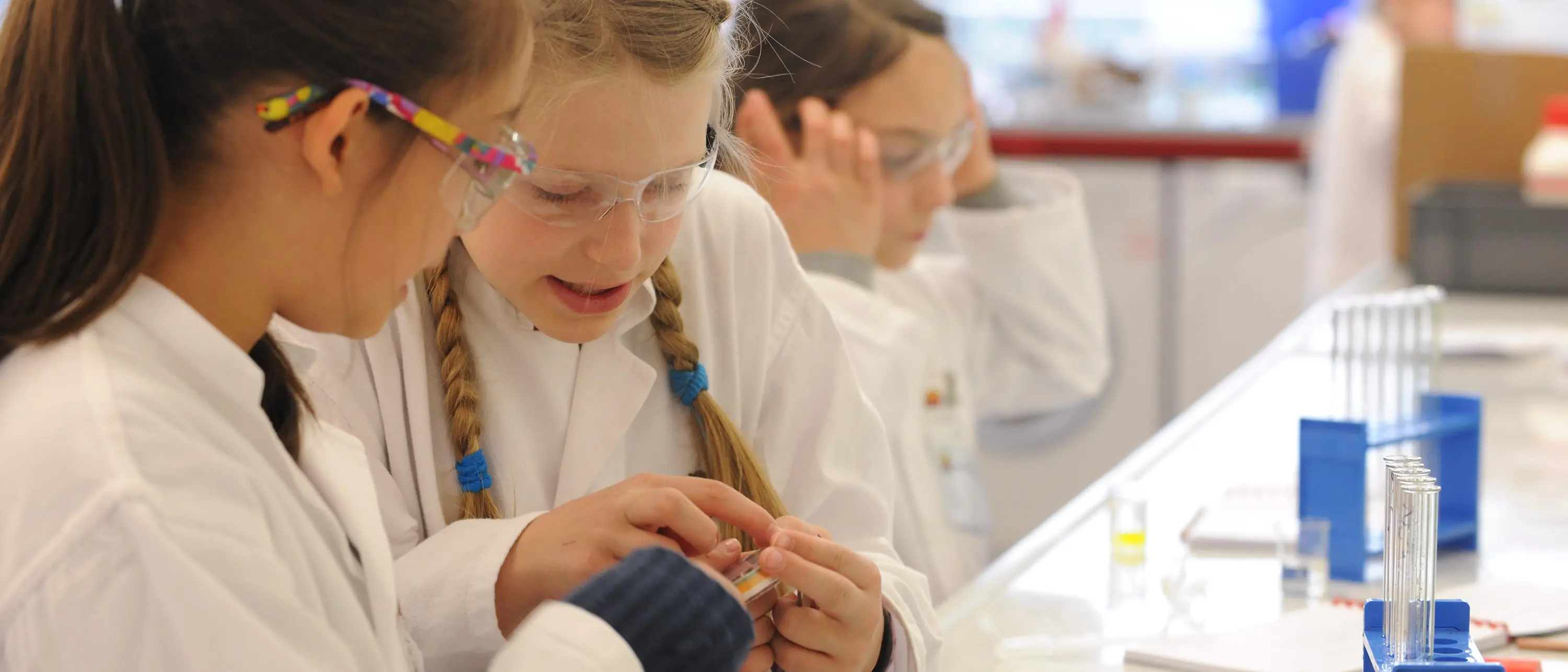 dwie dziewczyny w fartuchach laboratoryjnych na ławce