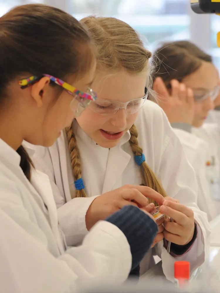 two girls in lab coats at bench