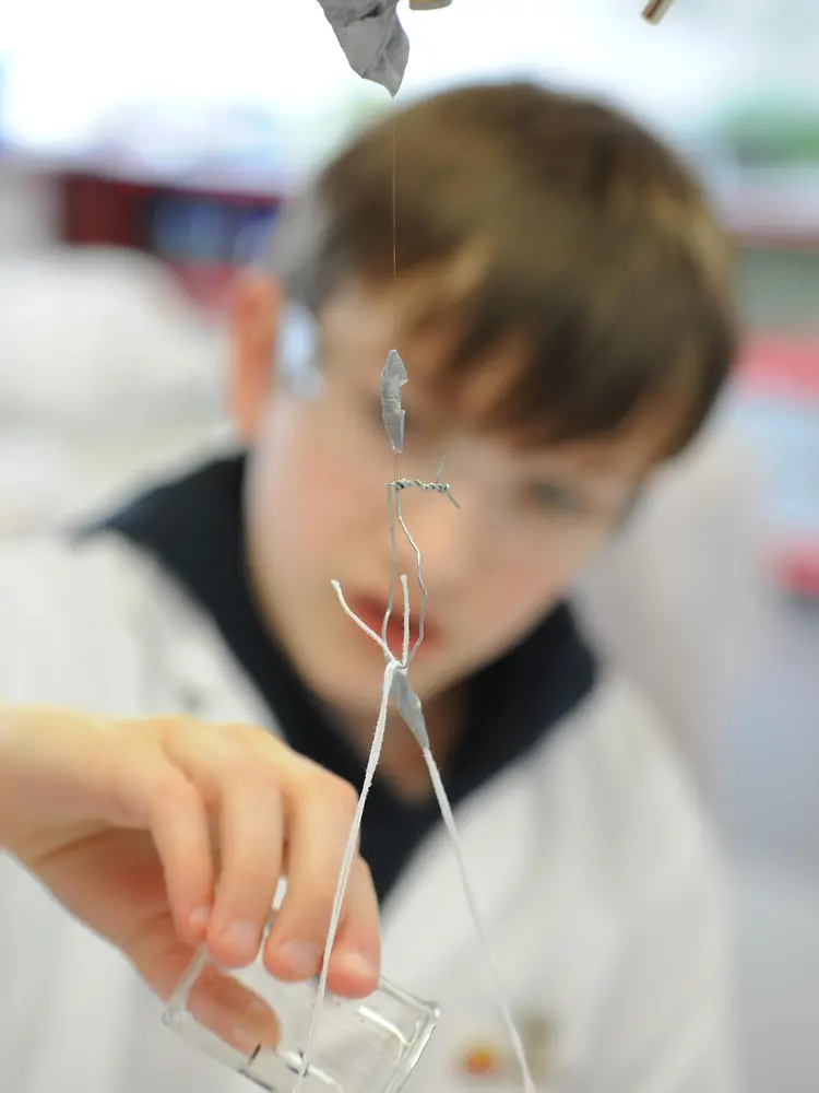 boy in lab coat besides a stand