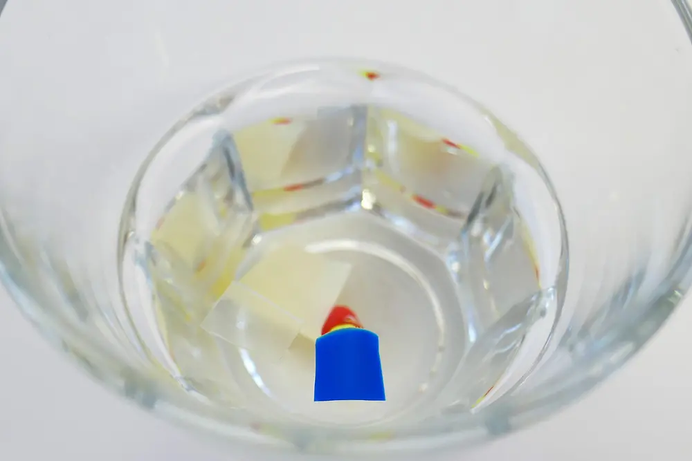 plastik parçaların suyun üzerinde durduğu bardak 
