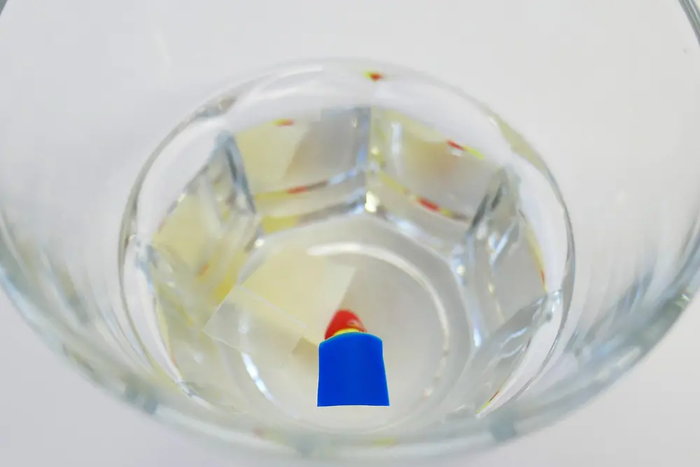 Wasserglas mit Plastikstücken