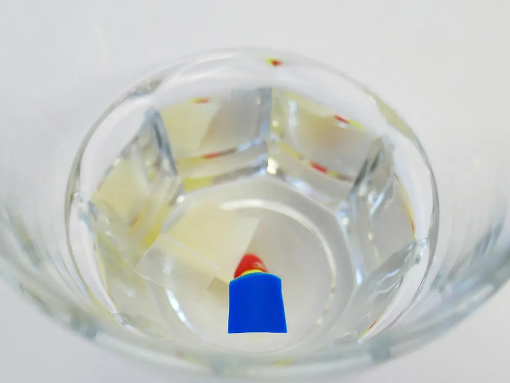 glas with plastic pieces floating on water