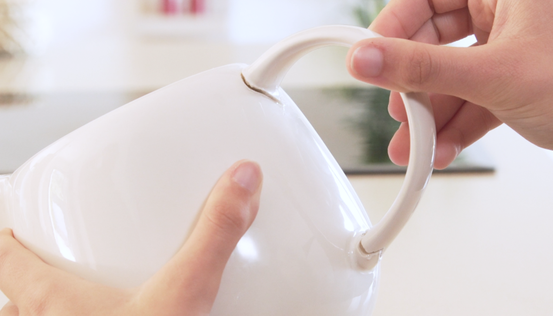 close up of hand gluing a handle to a white mug