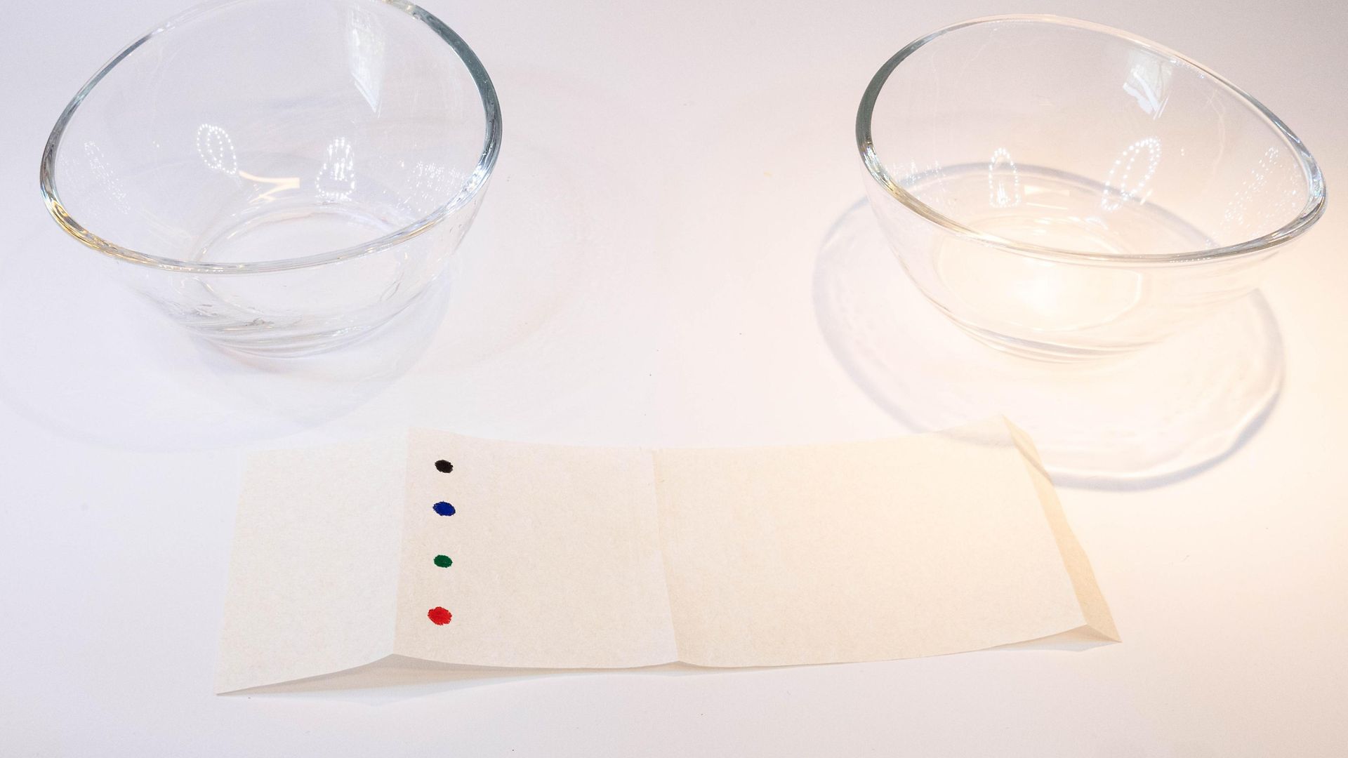 бумажная полоса с разноцветными точками перед двумя стеклянными чашами