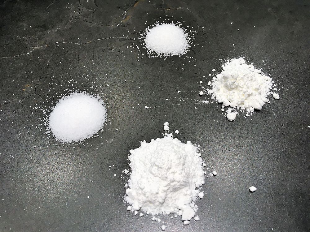 four white powders on black surface
