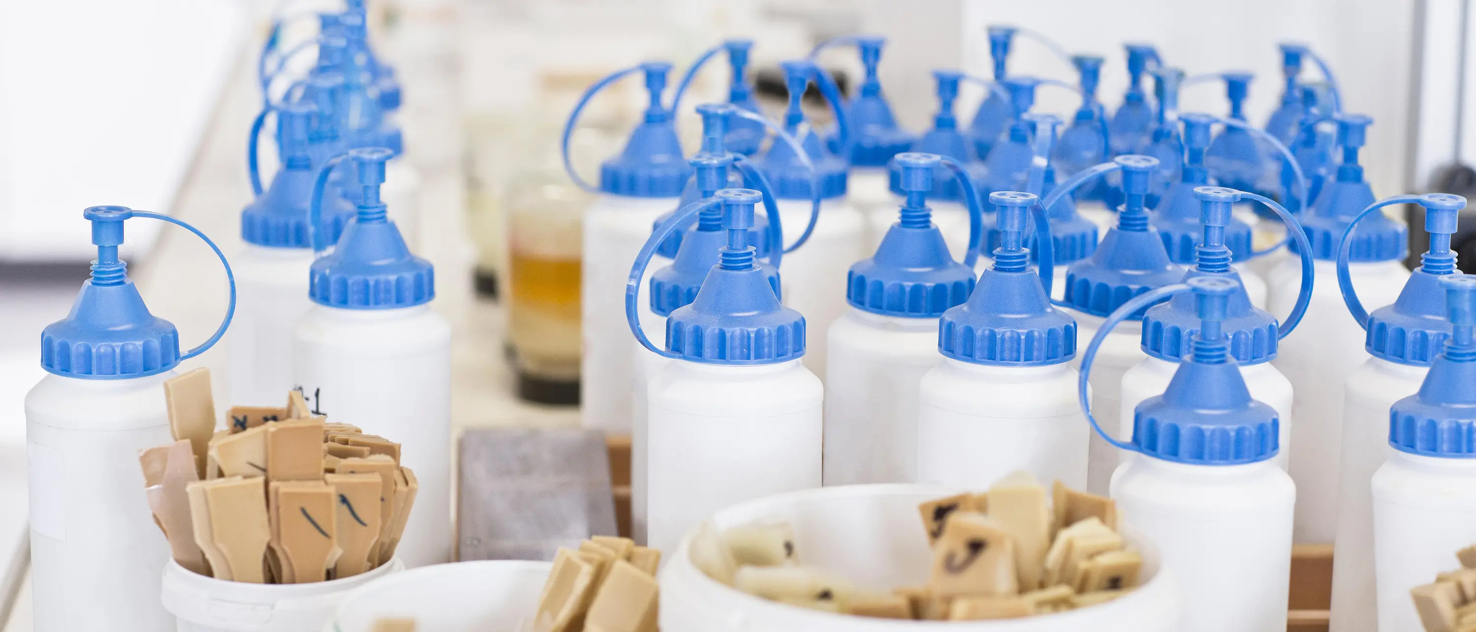 garrafas de plástico brancas com tampas azuis sob copos com pequenas espátulas de madeira
