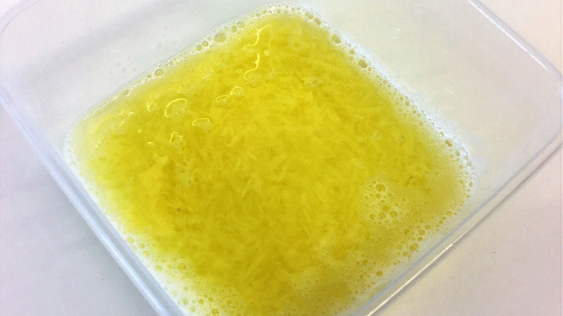 plastic bowl containing grated potato in water