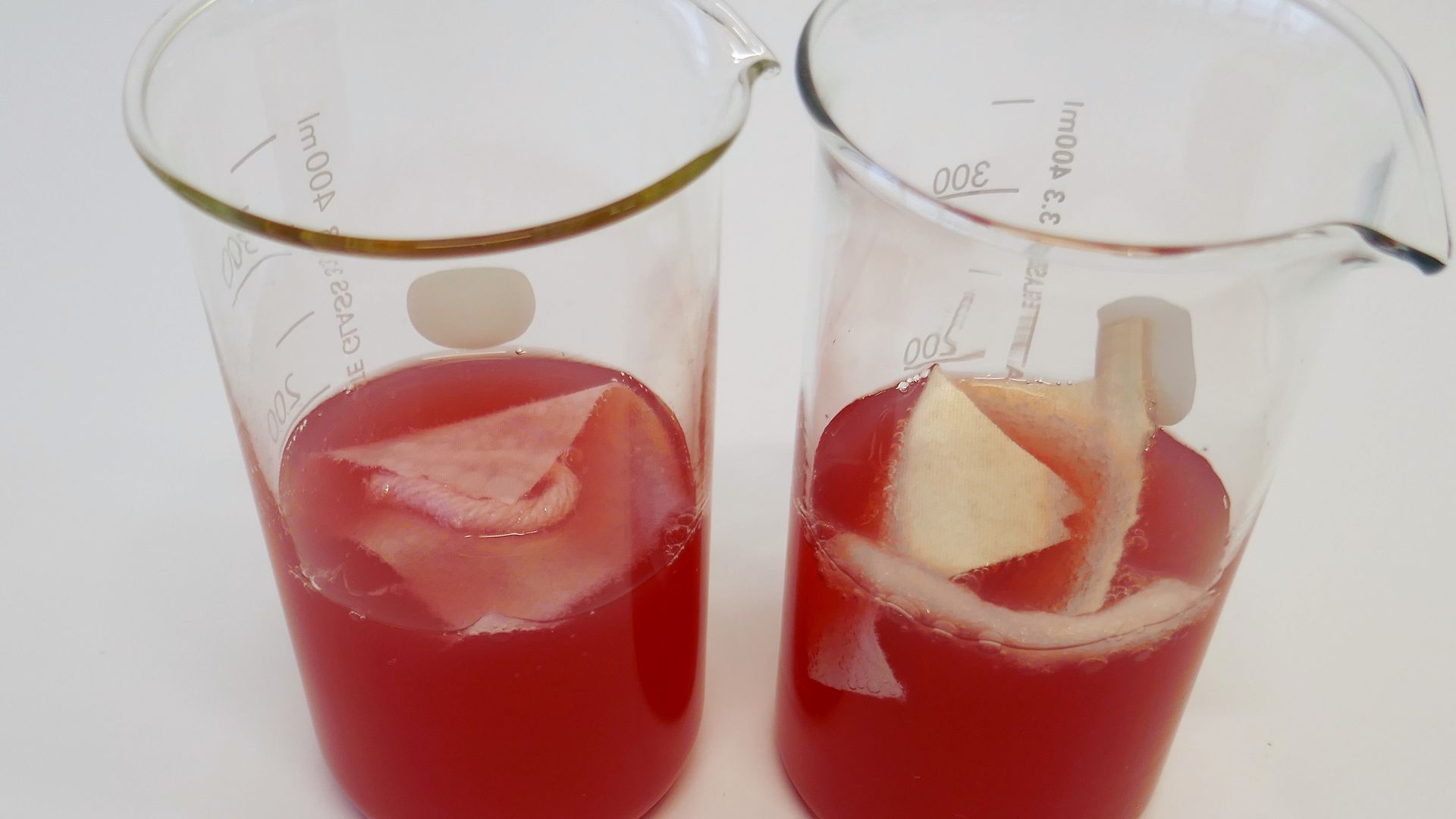 Zwei Gläser mit roter Limonade und Baumwoll- und Wollfäden