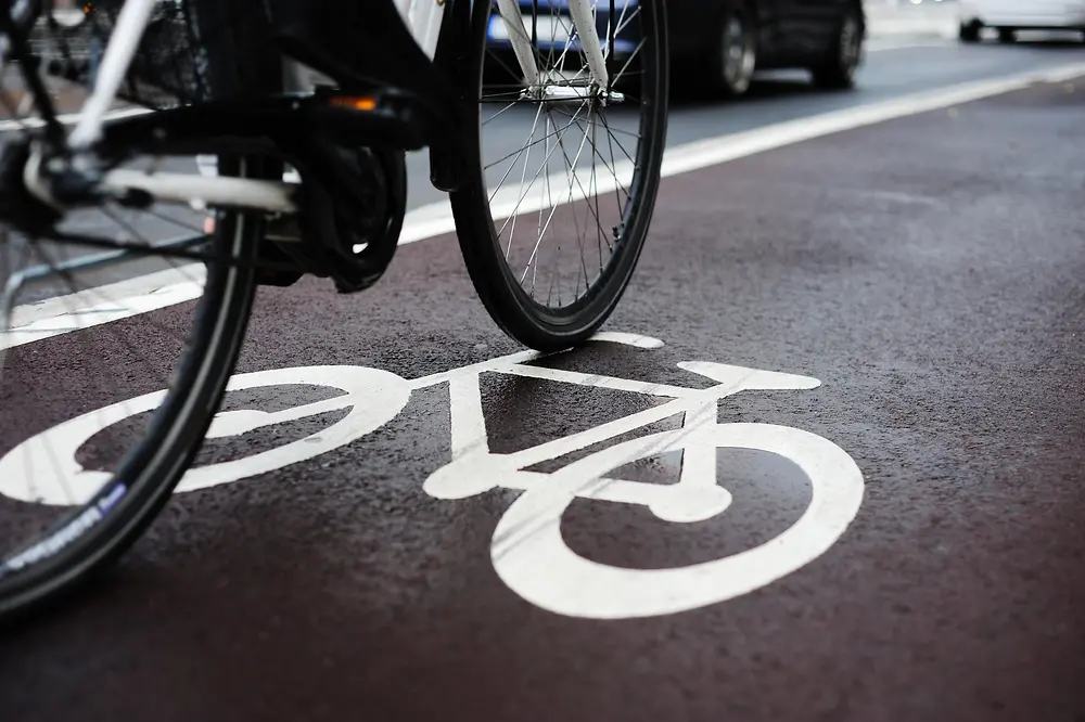 część roweru na czarnym asfalcie z pomalowaną ikoną roweru