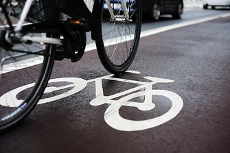 part of bicycle on black tarmac with painted bicylce icon