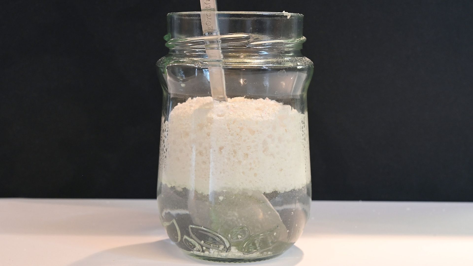 glass jar containing liquid and white foam