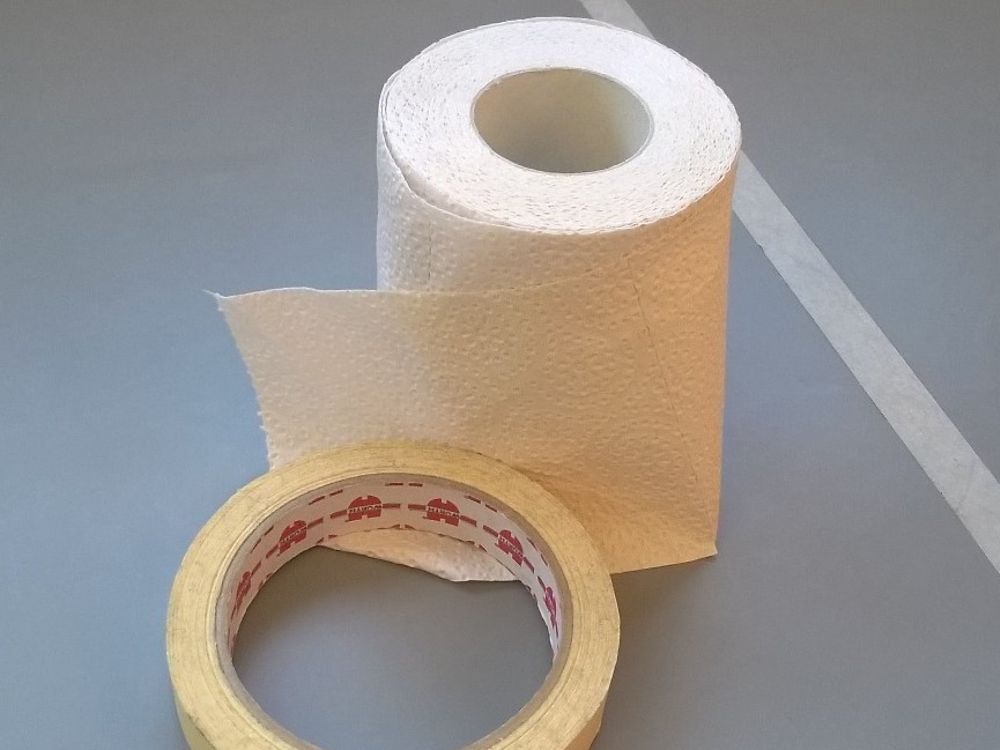 cinta adhesiva y rollo de papel higiénico en el piso
