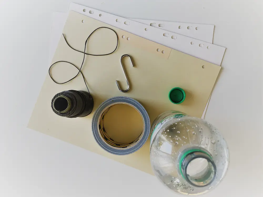 kağıt, koli bandı, makas, et kancası ve kalın kağıt üzerinde duran plastik şişe