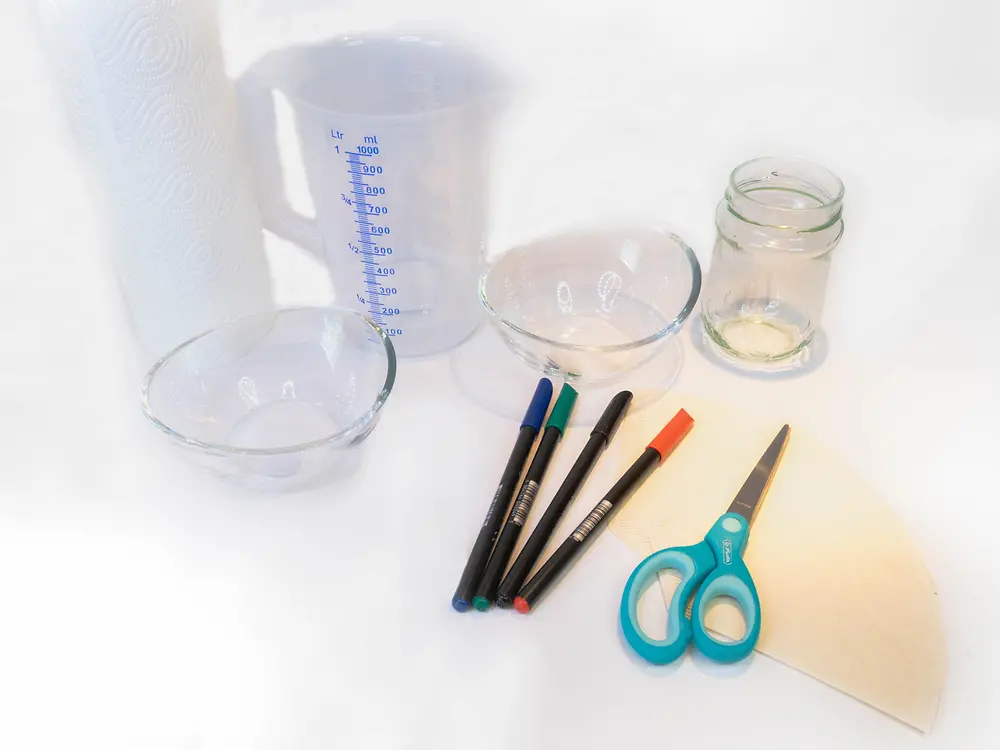 jarro medidor, canetas hidrográficas, tesoura, filtro de café e taças de vidro