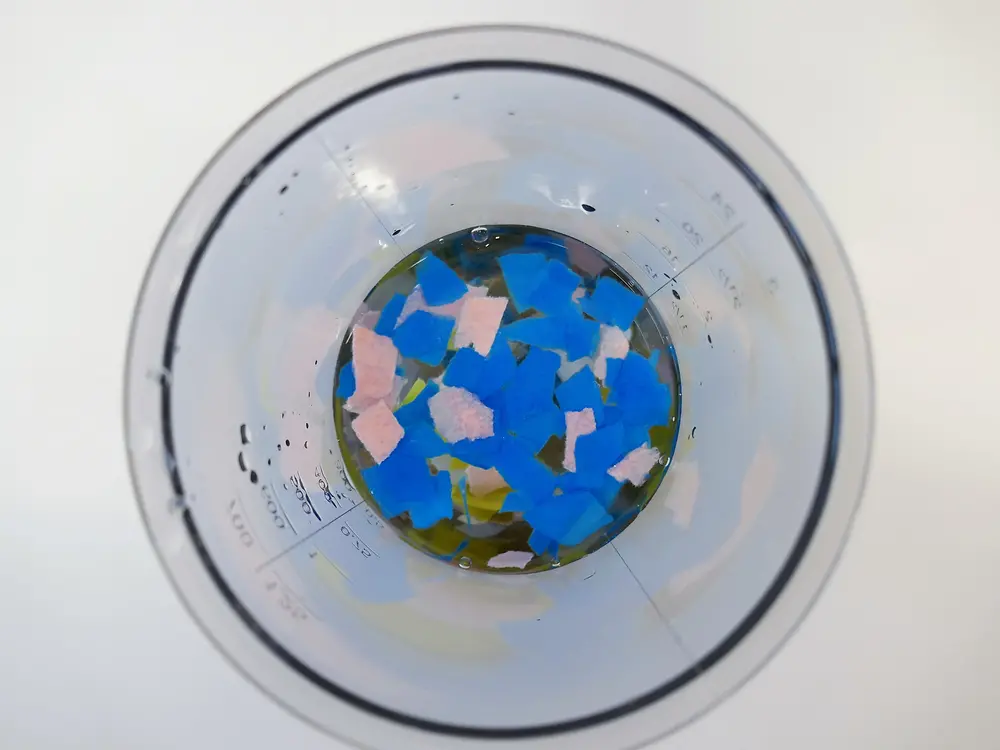 look from above into plastic jug containing colored pieces of paper