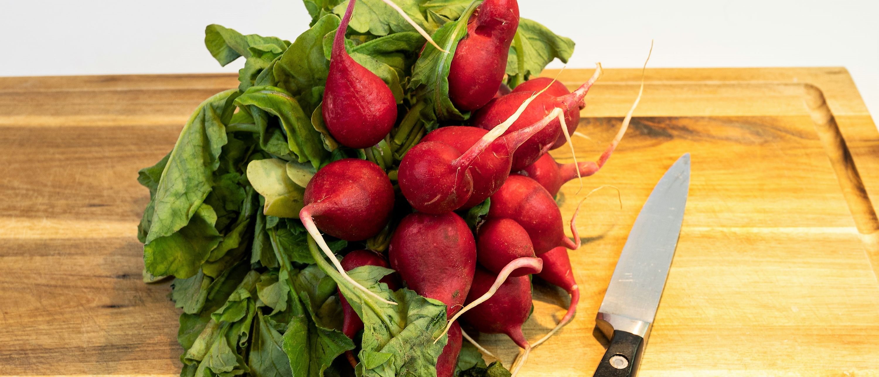 radish on wooden cutting board with knife