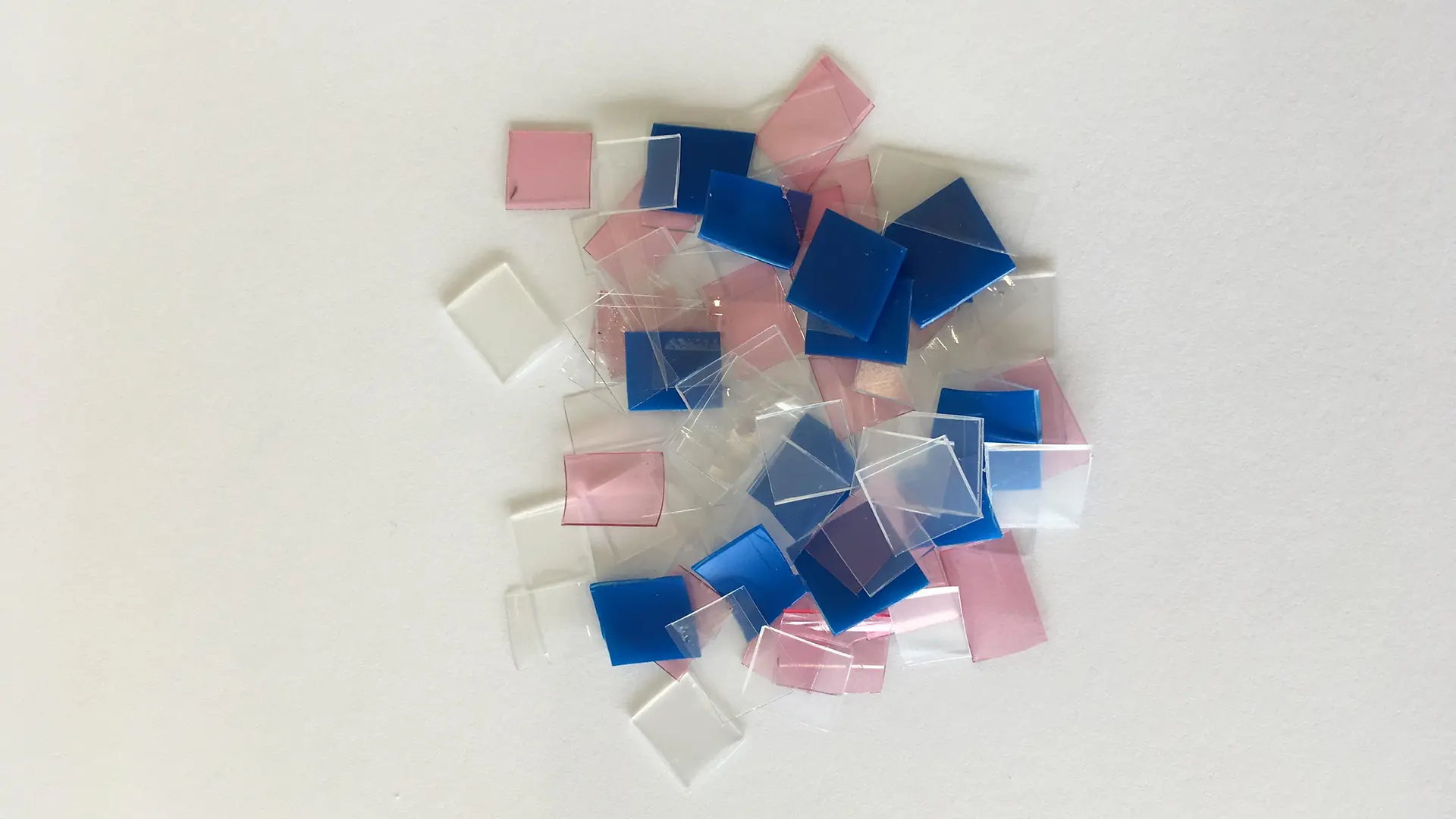 pequenos recortes de plástico azul, rosa branco e transparente
