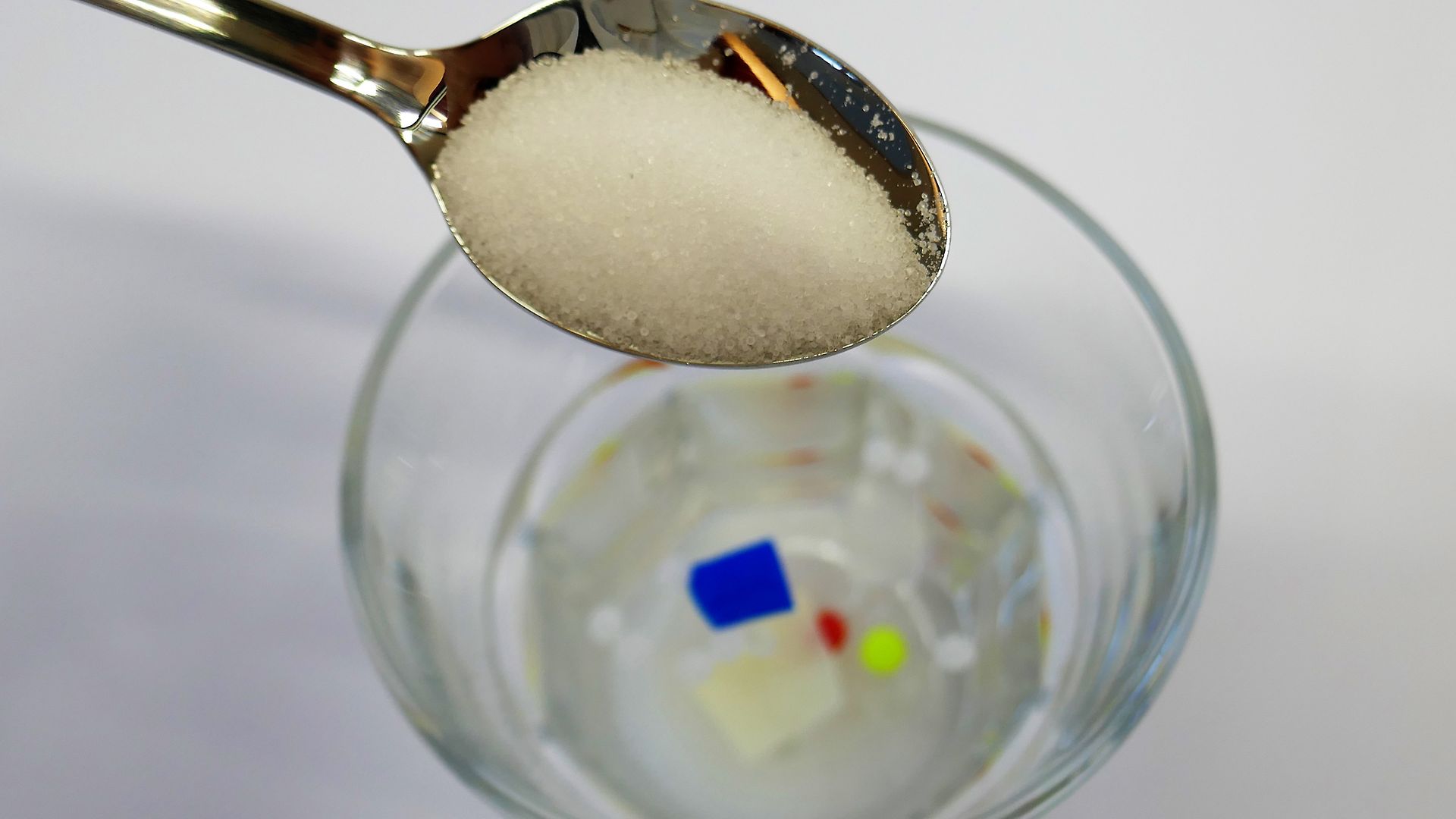 Teelöffel mit Salz wird zu Wasserglas mit Plastik gegeben