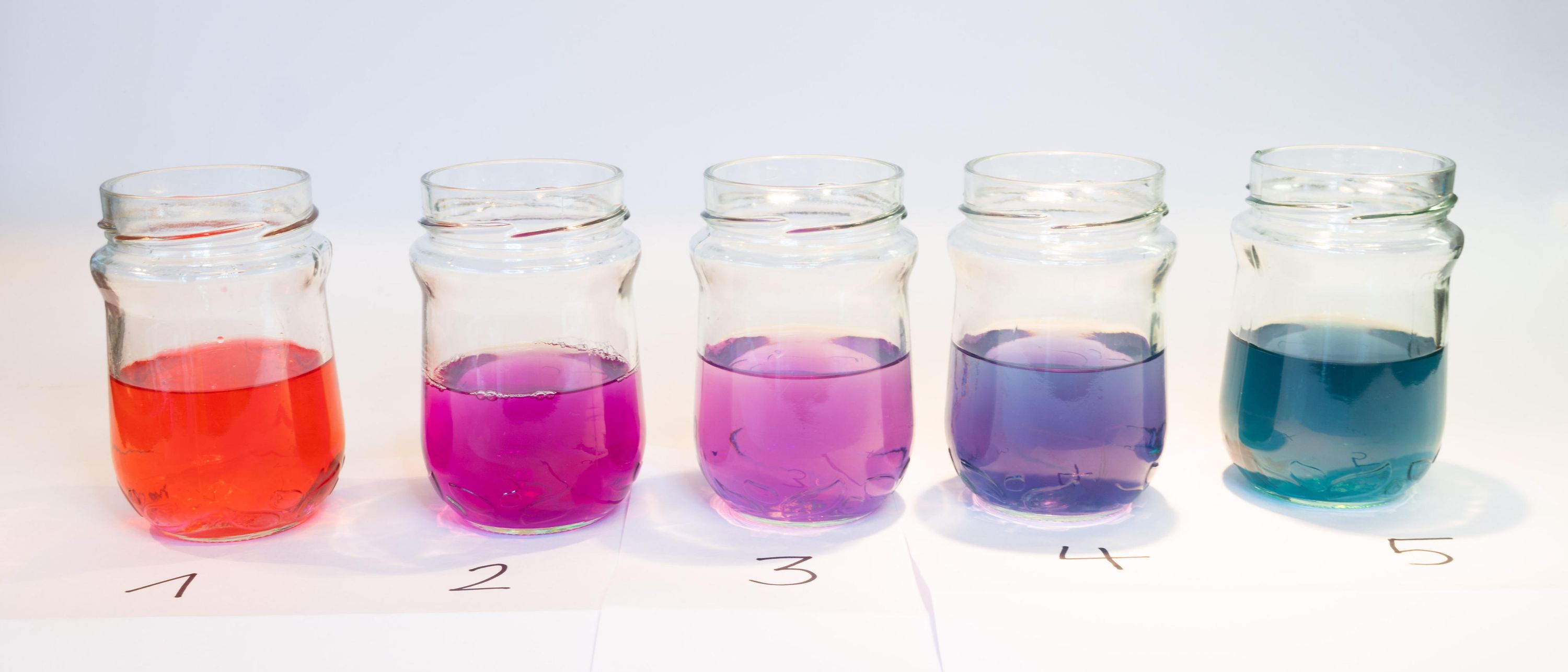 five glass jars with different colored liquids