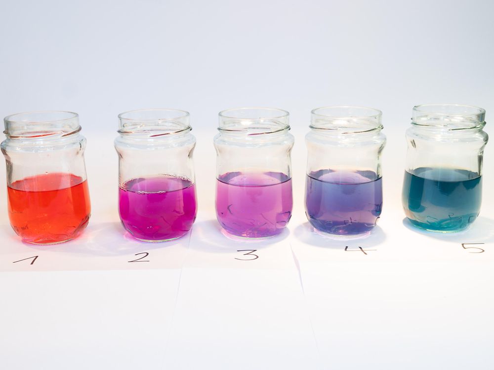 пять стеклянных банок с разноцветными жидкостями