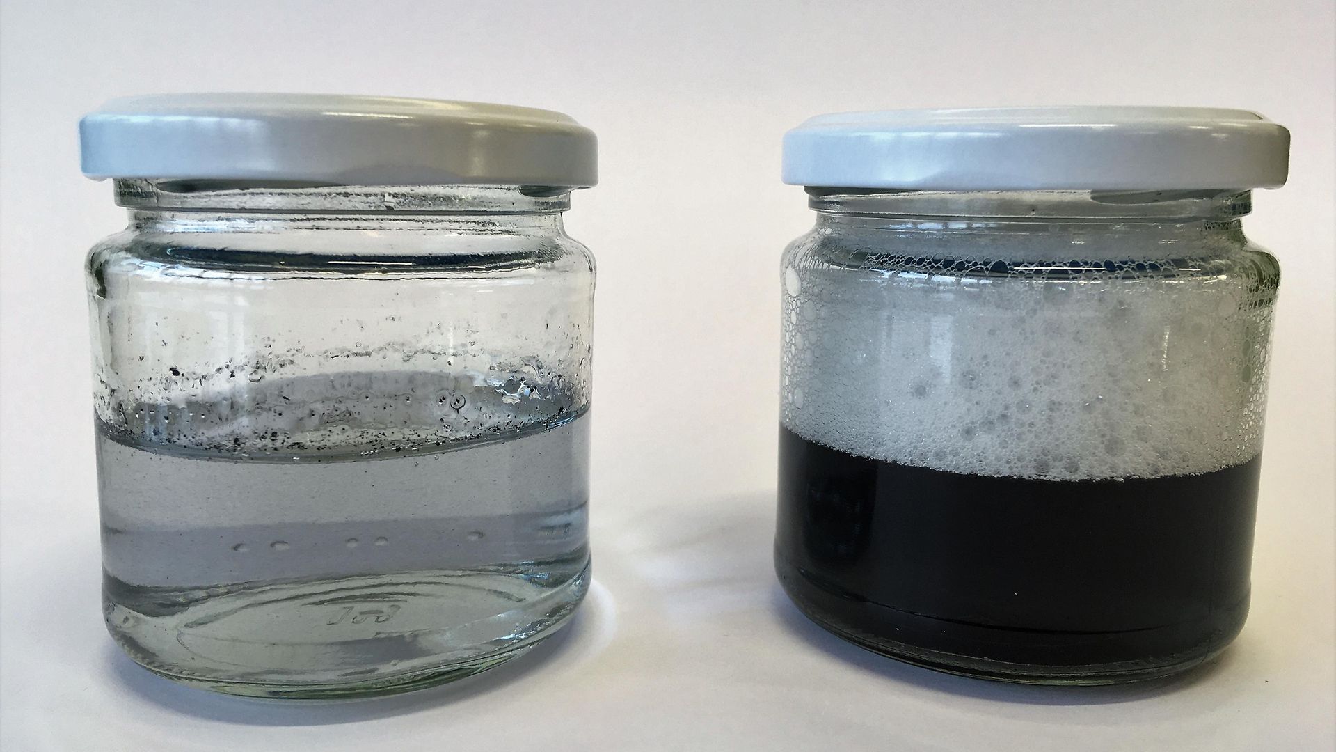 dos frascos de vidrio con hollín en agua y espuma
