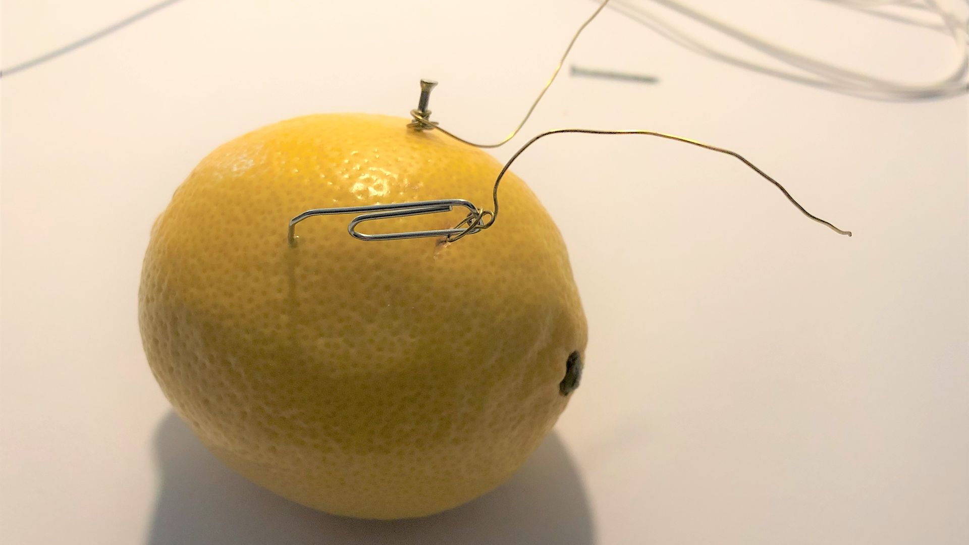 Zitrone mit Nagel, Büroklammer und Drähten