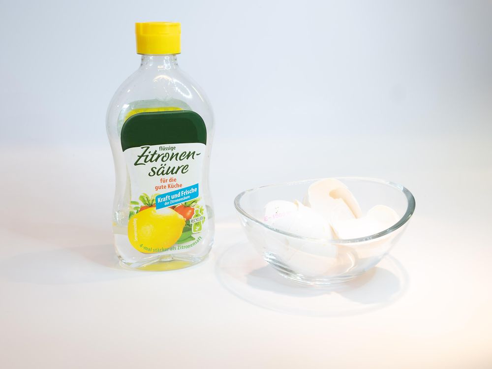 bottled citric acid and eggshells in glass bowl