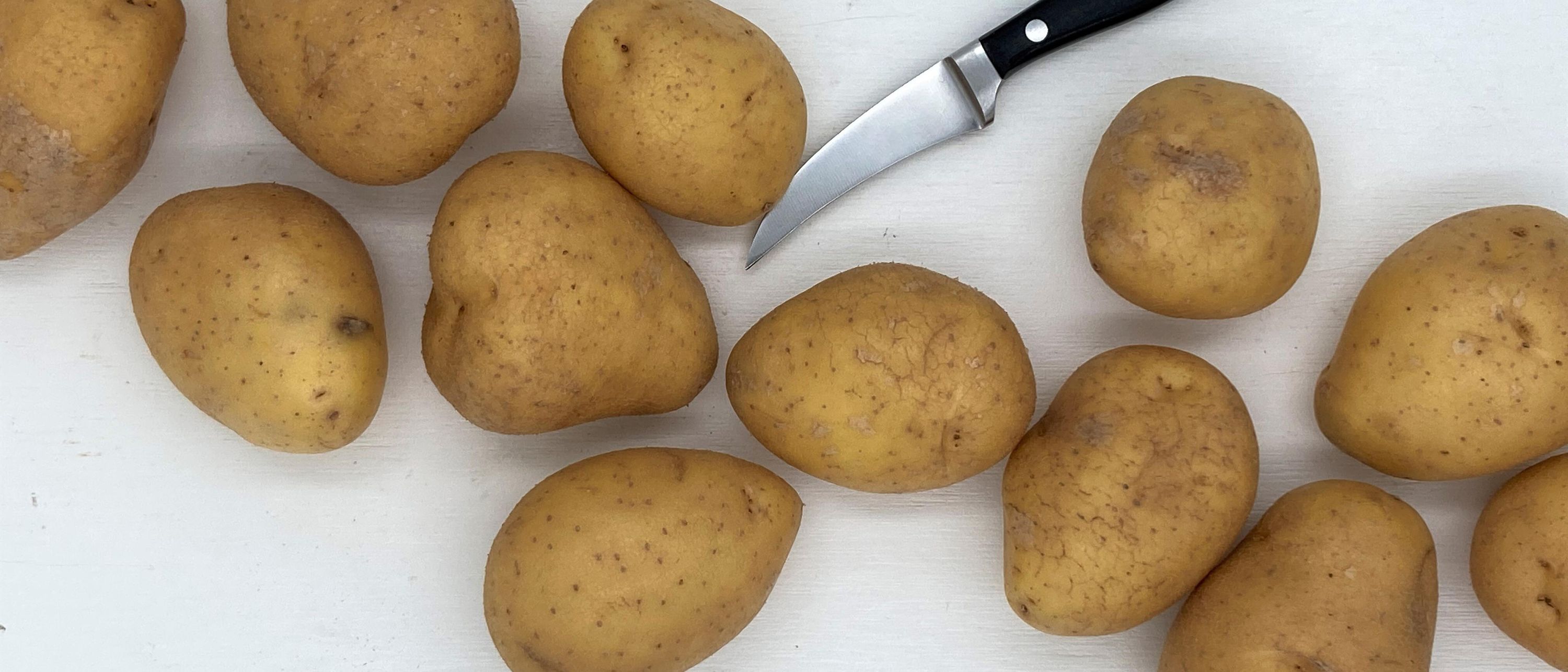 potatoes laying on white tray with kitchen knife