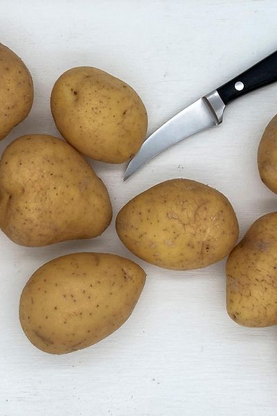 potatoes laying on white tray with kitchen knife