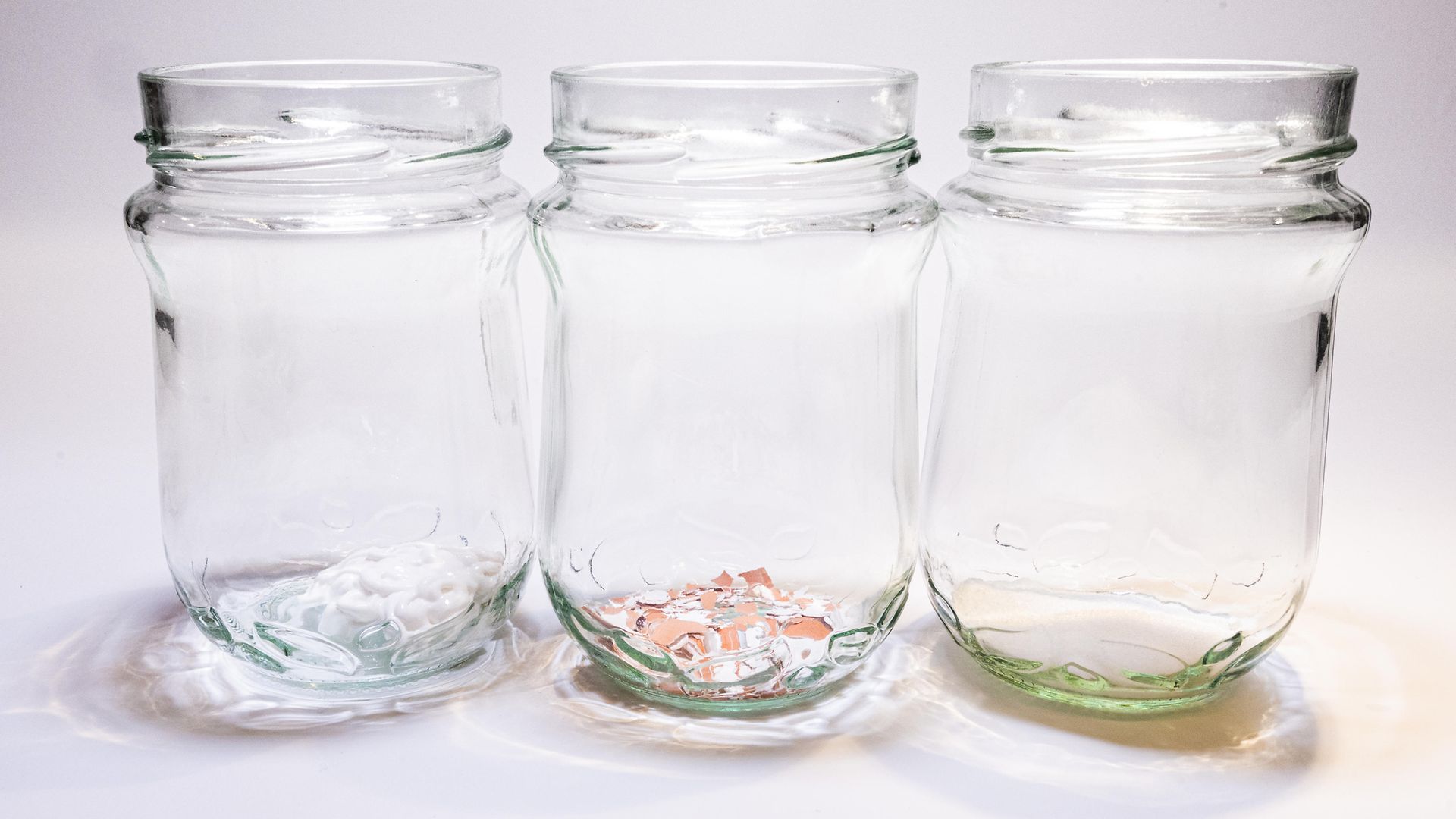 three glass jars with liquid, eggshell powder and toothpaste