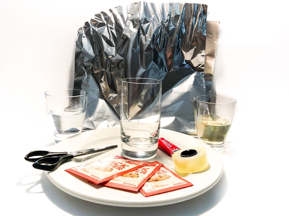 plate with baking powder packages, scissor, glasses in front of aluminum foil