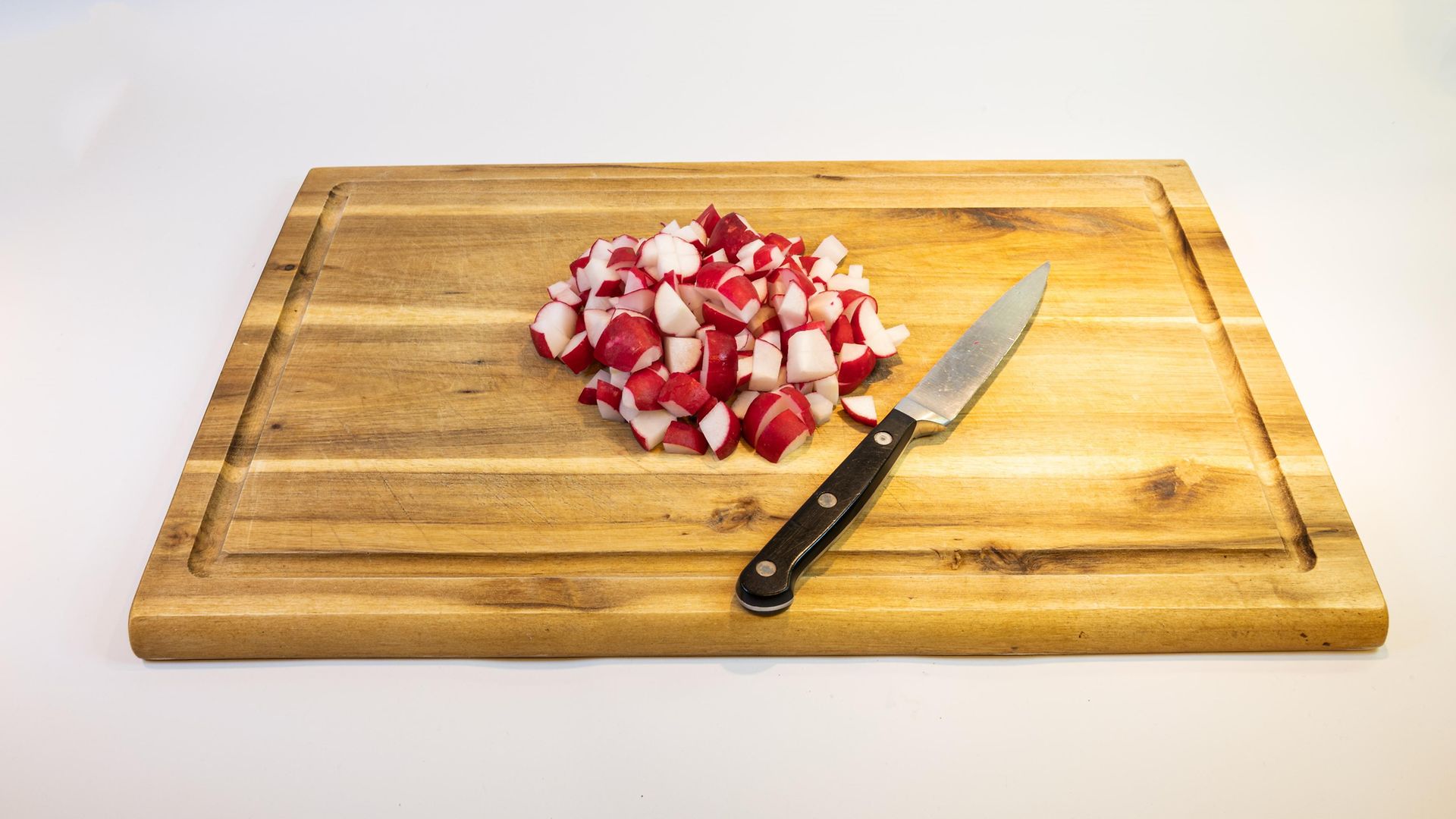 radish cut in small pieces on wooden cutting board