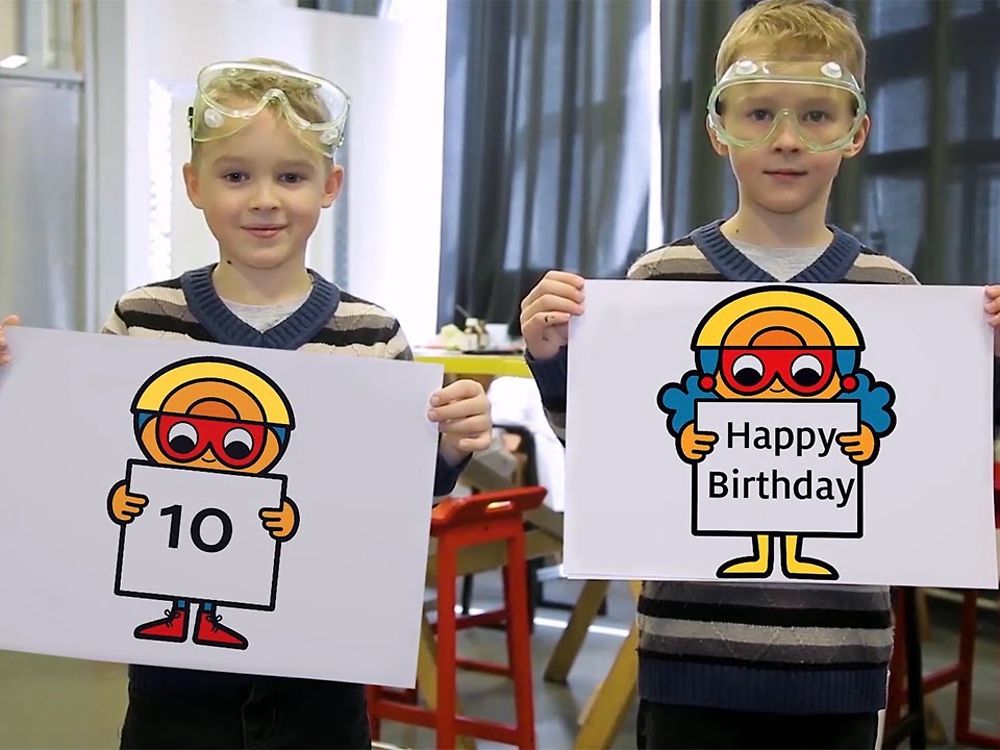 2 blond boys holding paintings with the Text 10 and Forscherwelt