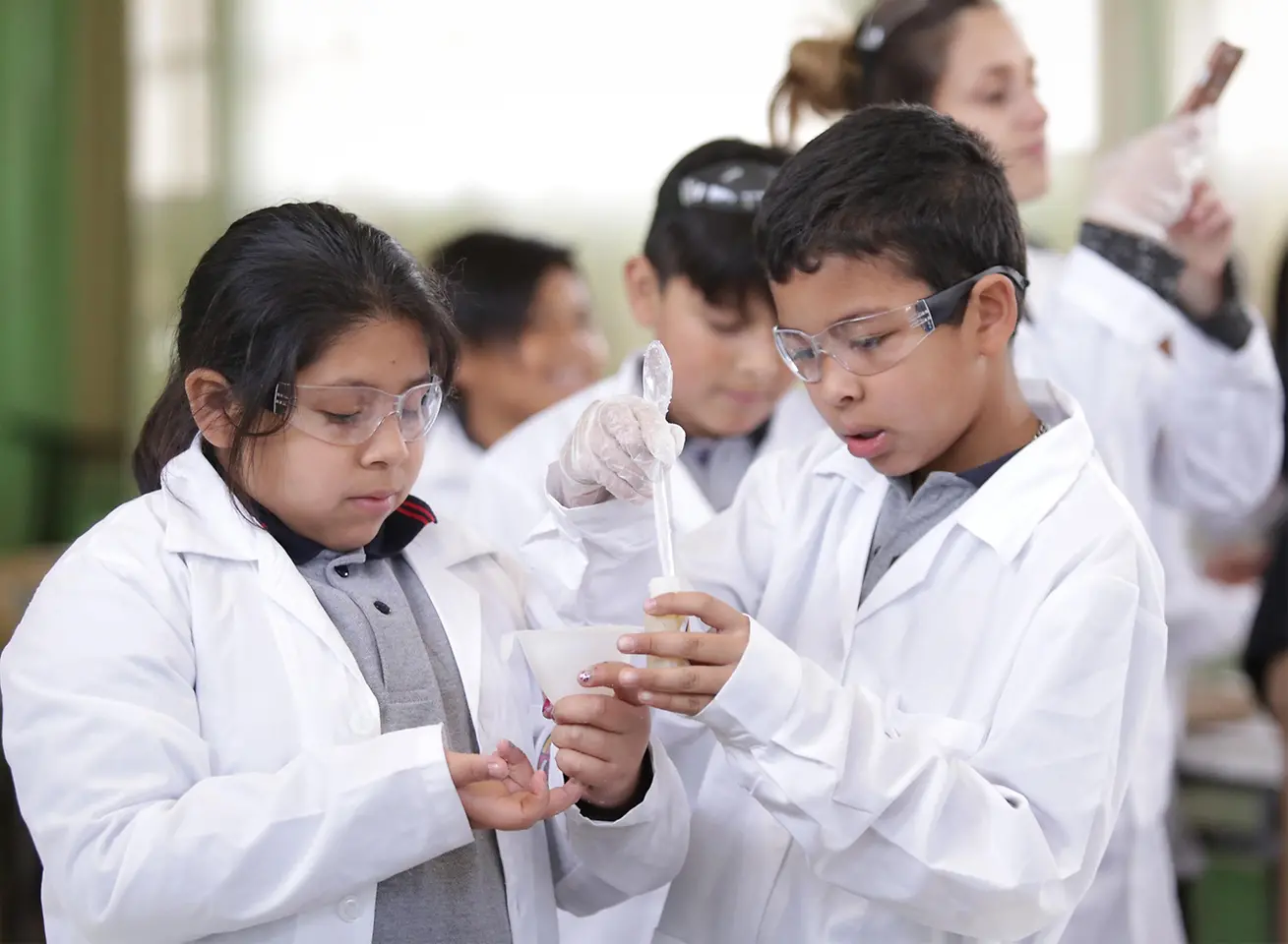 Club Henkel Mundo de Investigadores América Latina: niños con batas de trabajo blancas hacinedo experimentos.