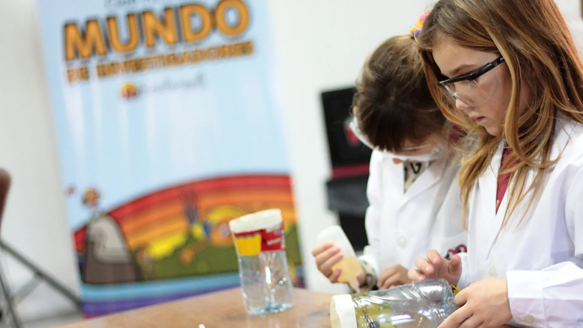 Club Henkel Mundo de Investigadores América Latina: dos niños están haciendo un experimento con un frasco con tapa.