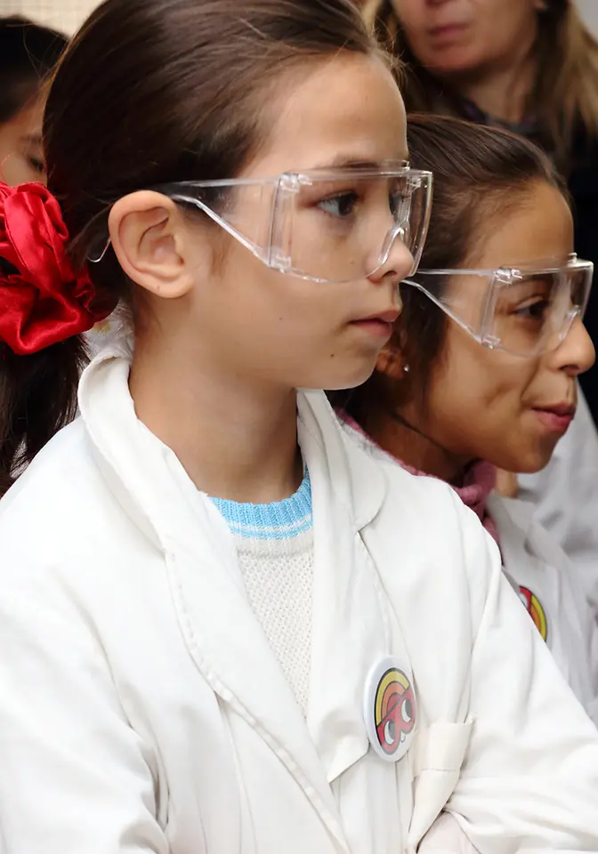Club Henkel Mundo de Investigadores América Latina: dos chicas con gafas viendo un experimento con asombro.