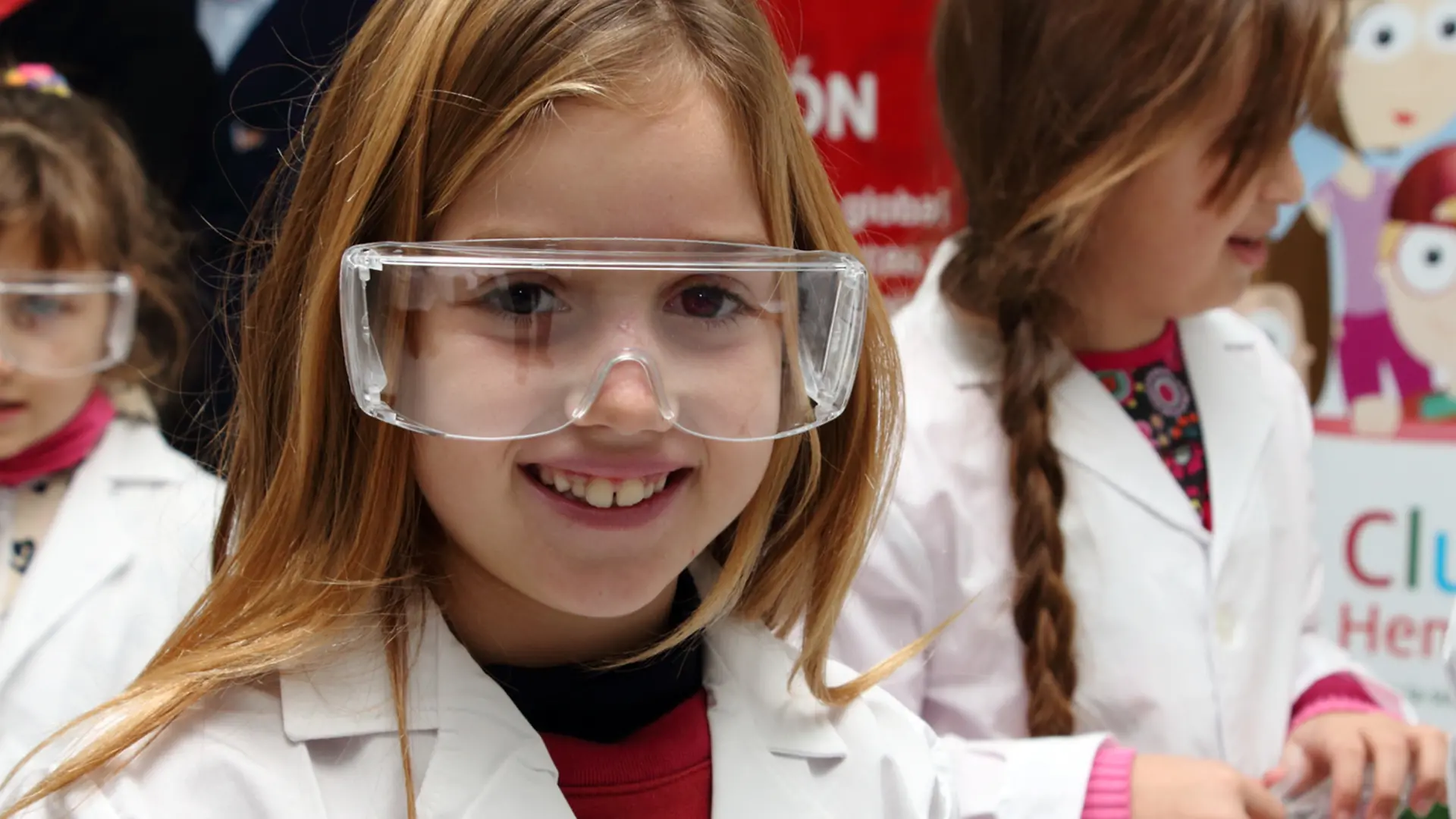 Club Henkel Mundo de Pesquisadores América latina: Menina com óculos de segurança grandes rindo da câmera.