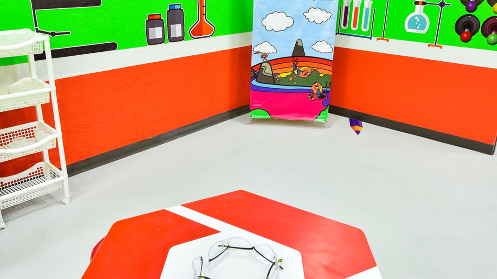 Club Henkel Mundo de Pesquisadores América latina: sala para experimentos com paredes verdes e móveis laranja.