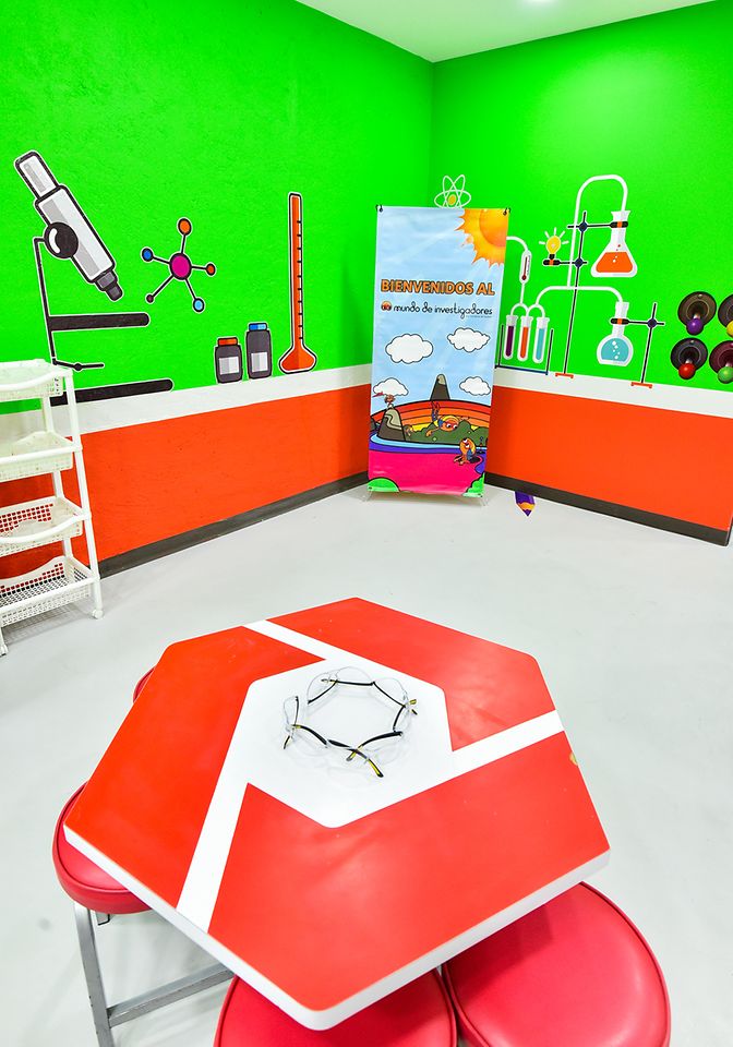 Club Henkel Mundo de Pesquisadores América latina: sala para experimentos com paredes verdes e móveis laranja.