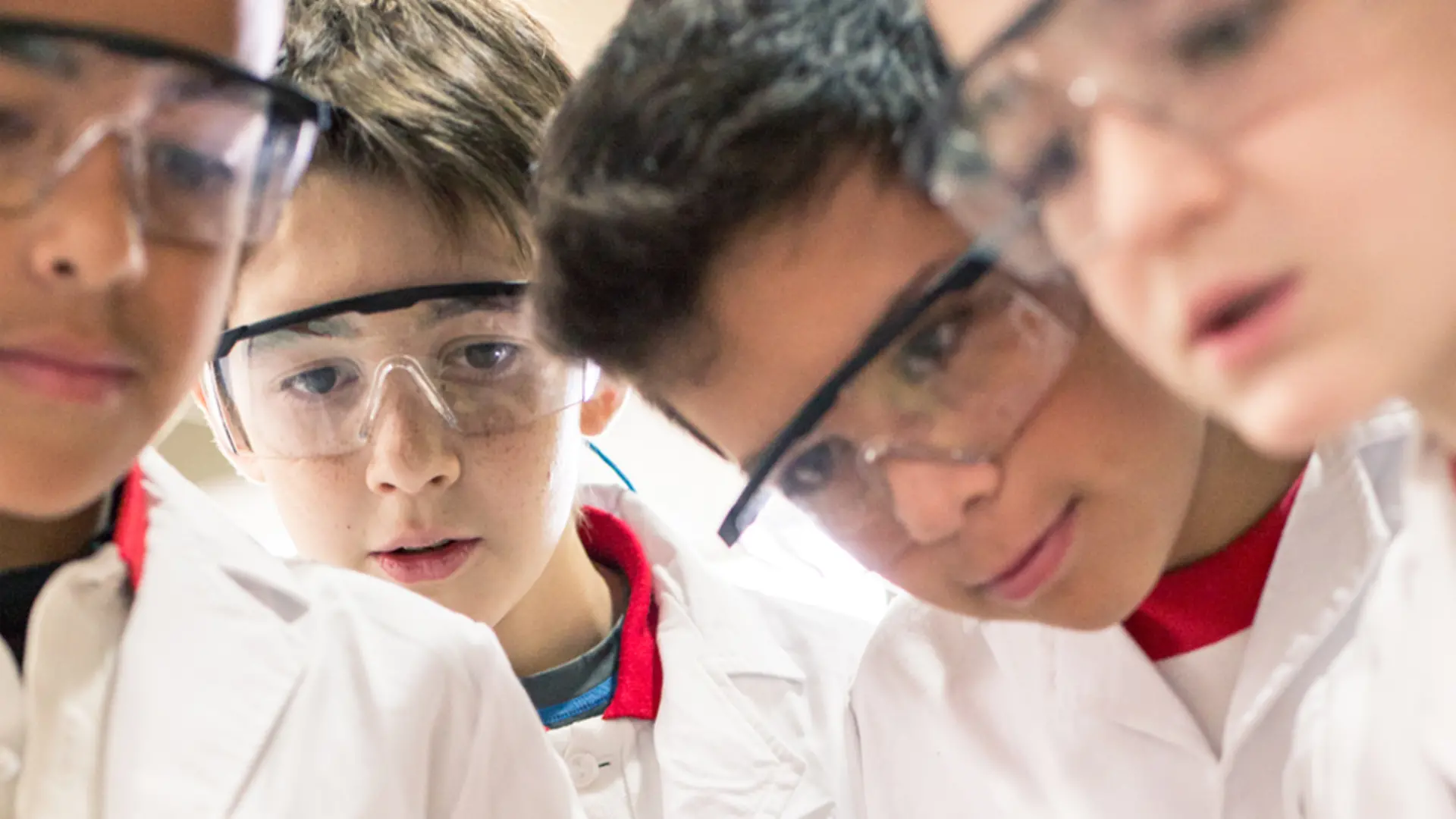 Club Henkel Mundo de Pesquisadores América latina: quatro crianças fazendo um experimento juntas e despejando água em um copo.