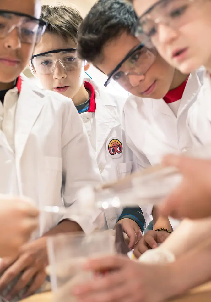 Club Henkel Mundo de Pesquisadores América latina: quatro crianças fazendo um experimento juntas e despejando água em um copo.