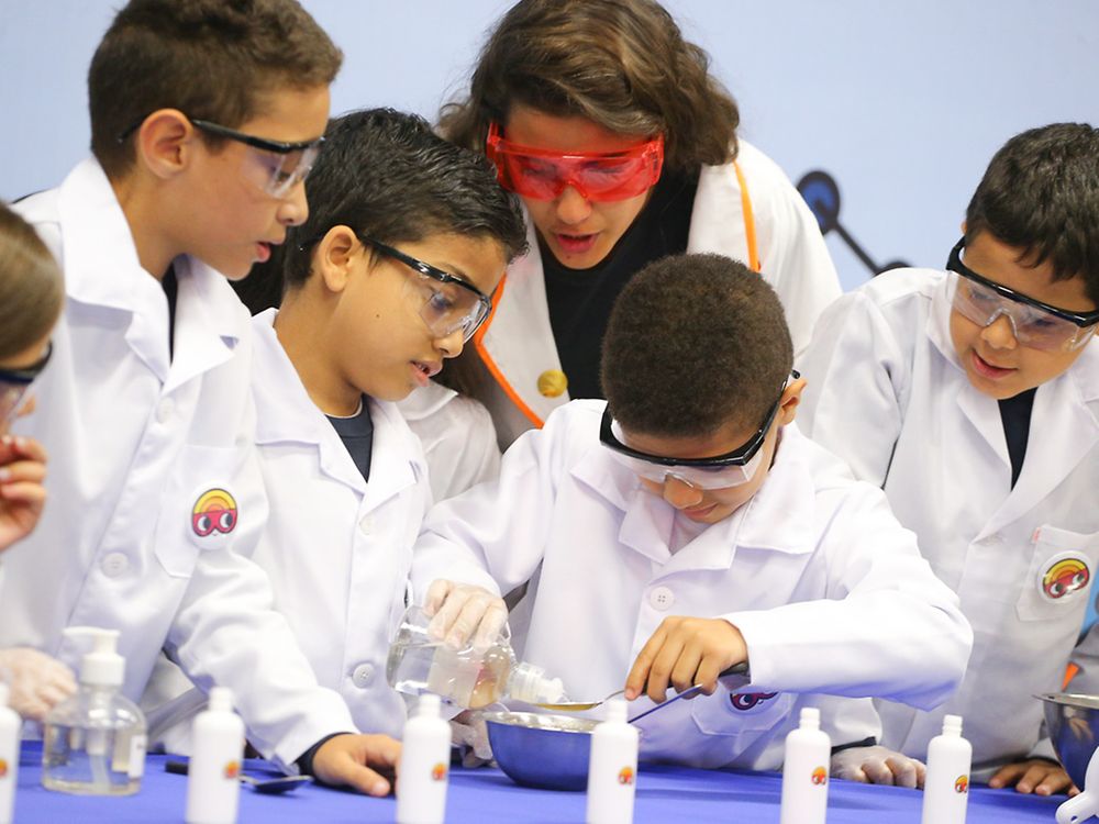 Como parte del mundo de la investigación, 5 estudiantes brasileños realizan un experimento adhesivo bajo la supervisión de su profesor. Un estudiante mezcla los componentes.