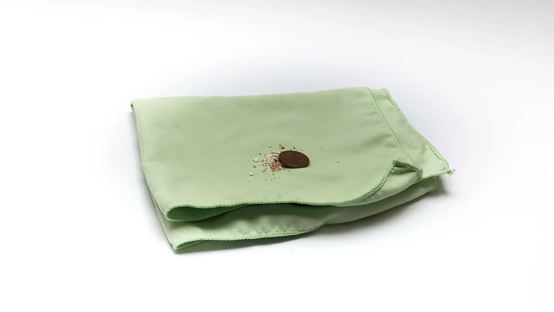 Зелена зволожена ганчірка для чищення з монетою та порошком з яєчної шкаралупи.