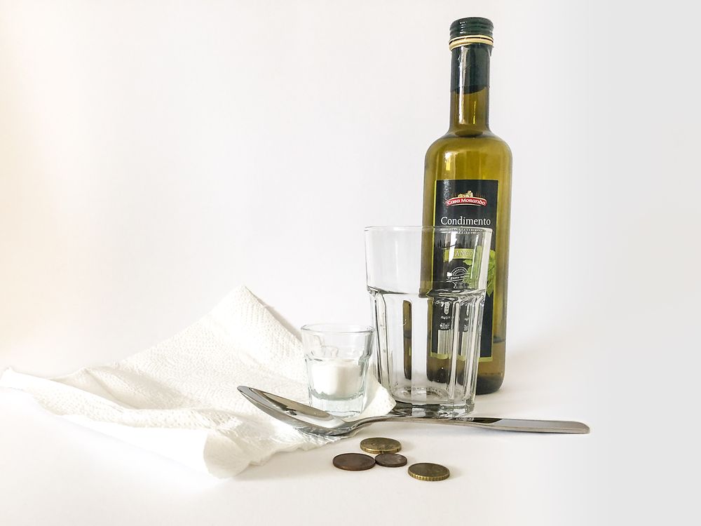 Butelka z octem, ściereczka do czyszczenia, szklanka, łyżka stołowa, monety i sól kuchenna w słoiku