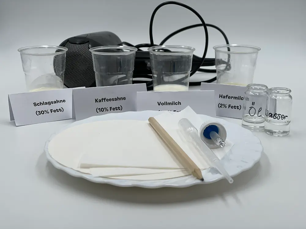 various milk packs, bottle with cooking oil, water glass, pipettes, filter papers, hair dryer.