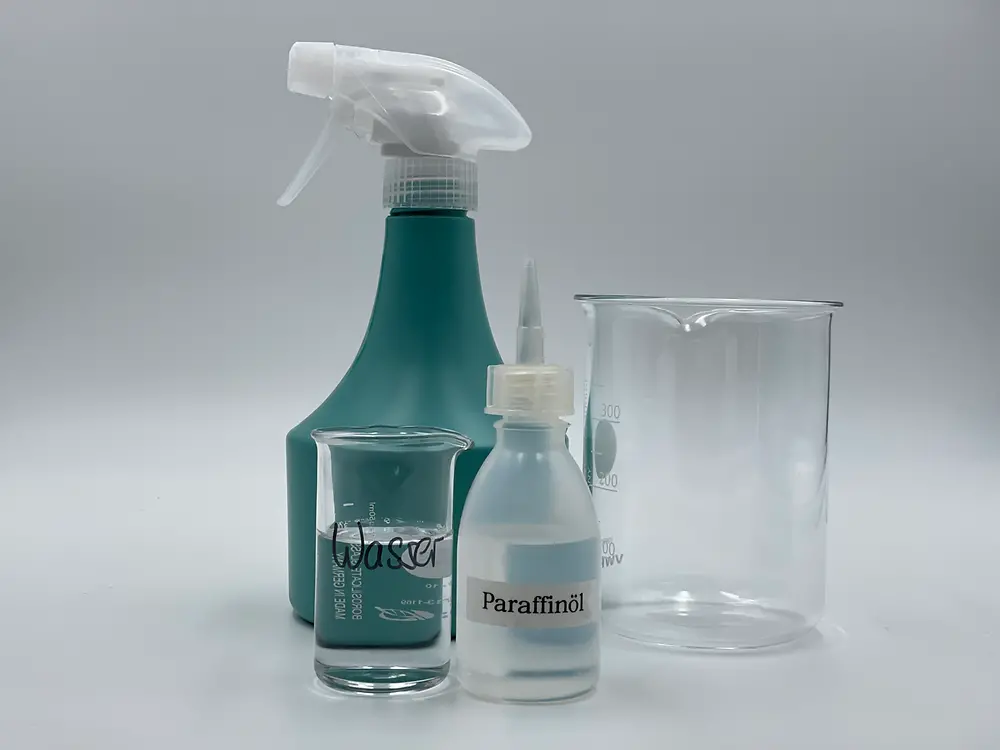 a small glass with water, a small glass with a little oil, an empty spray bottle