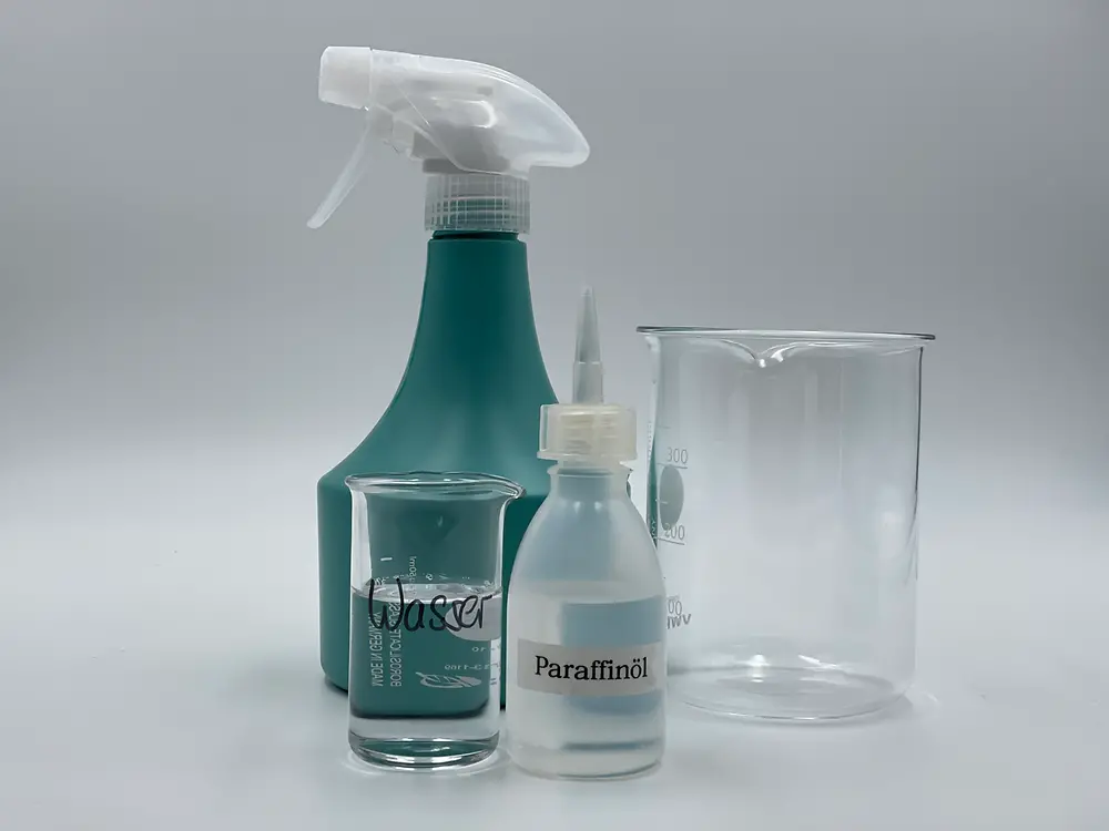 ein kleines Glas mit Wasser, ein kleines Glas mit wenig Öl, eine leere Sprühflasche