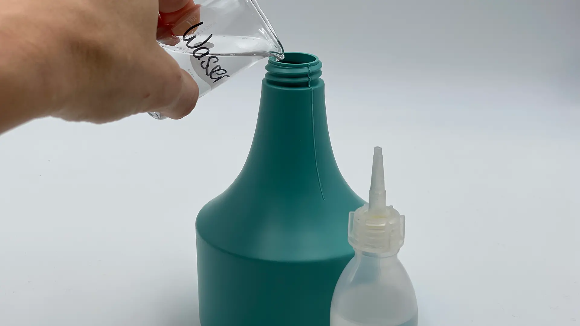 Sprühflasche, die per Hand mit Wasser- und Öl-Mischung gefüllt wird