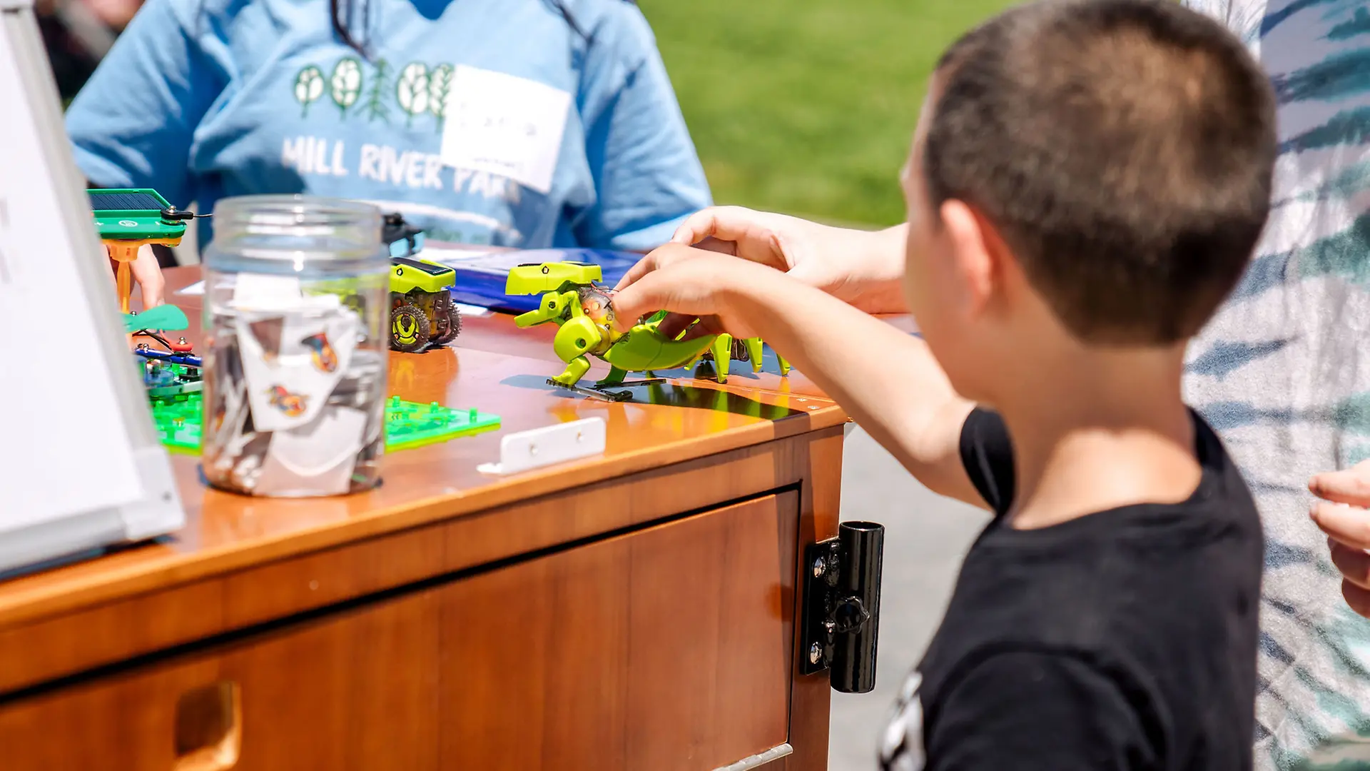 Student plays with a mechanical dinosaur toy.